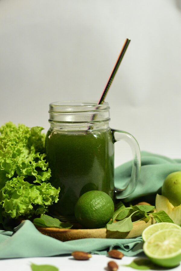 Refreshing green juice with lime and lettuce, served with a metal straw in a mason jar.