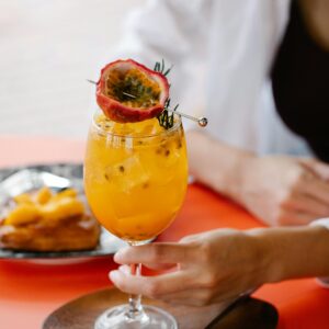 Vibrant passion fruit cocktail held above a wooden platter, perfect refreshment for a summer day.