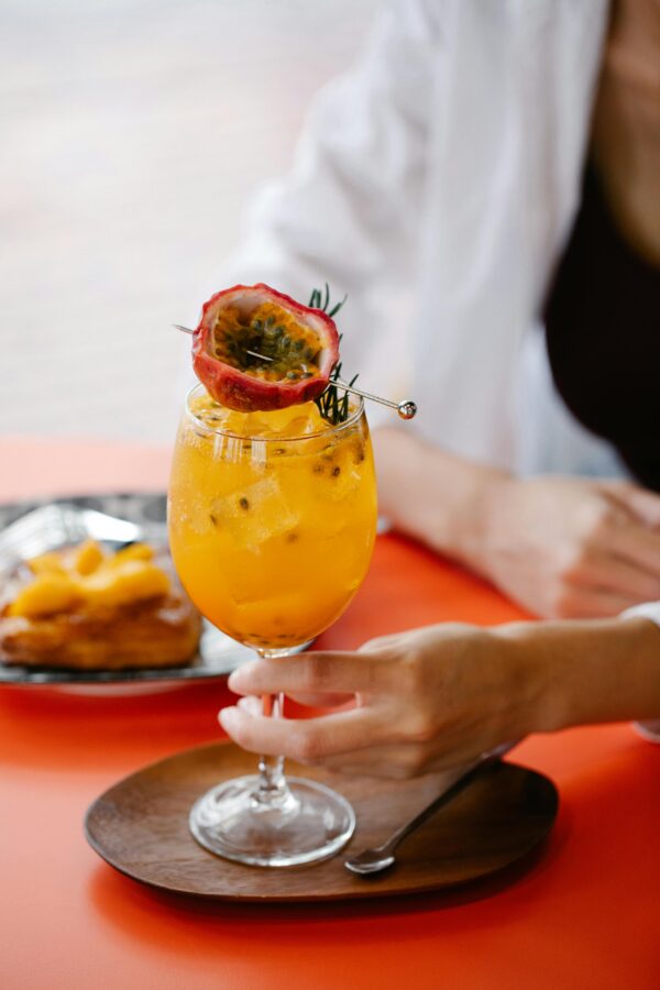 Vibrant passion fruit cocktail held above a wooden platter, perfect refreshment for a summer day.